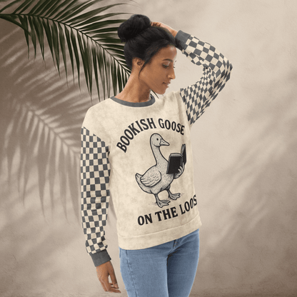 Woman wearing a sweater with a graphic and text, standing against a neutral background with a leaf.