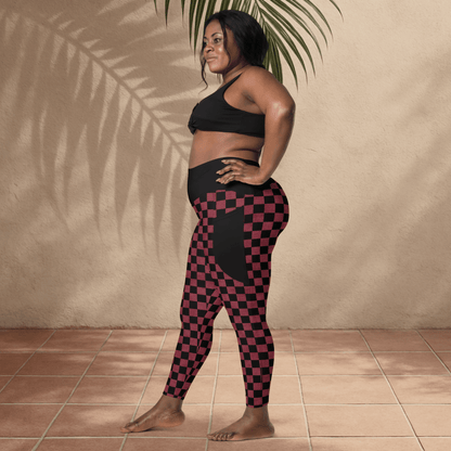 Woman wearing a black sports bra and checkered leggings standing against a beige wall.