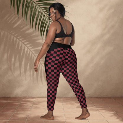 Person wearing black and burgundy checkered leggings against a beige wall.