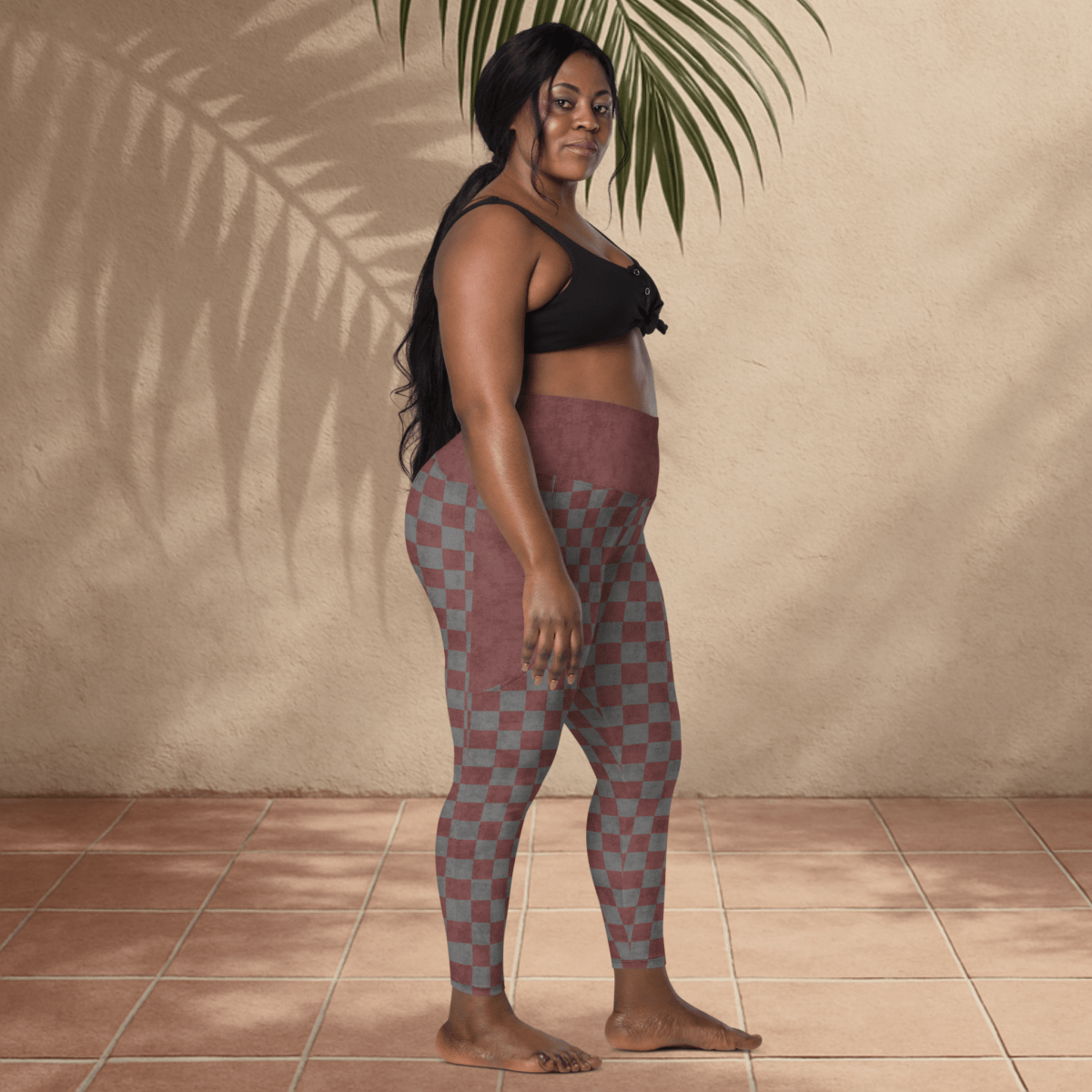 Woman wearing checkered leggings and a black top against a beige wall.
