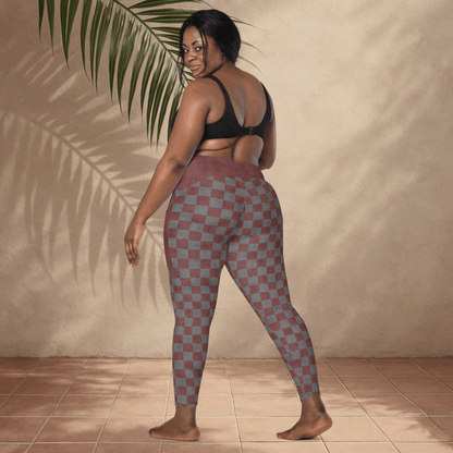 Woman wearing checkered leggings and black sports bra against a beige wall with a plant.