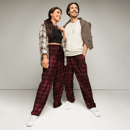 Two people wearing matching plaid pants and casual tops against a plain background