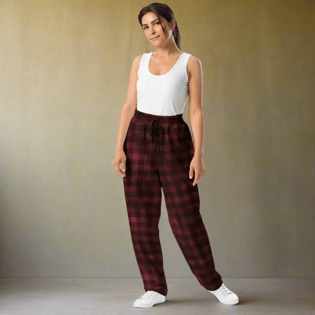 Woman wearing a white tank top and red plaid pants against a plain background