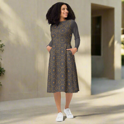 Woman wearing a patterned dress standing outdoors with a neutral background
