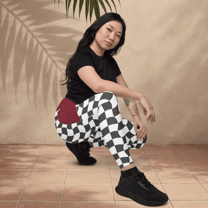 Person wearing black and white checkered pants with a red pocket, sitting on a tiled floor.