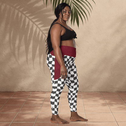 Woman wearing a black top and checkered pants standing against a beige wall.
