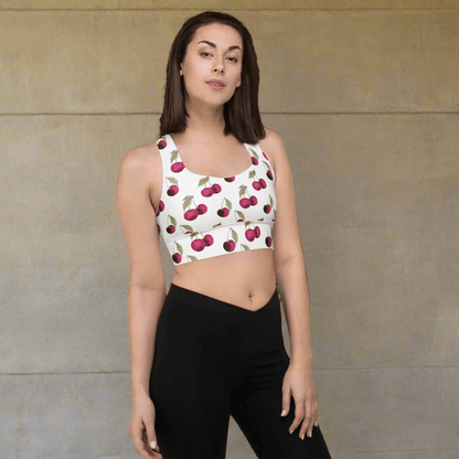 Woman wearing a sports bra with cherry pattern and black leggings on a beige background