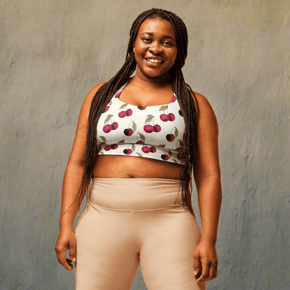 Woman wearing a white sports bra  with cherry pattern and beige pants on a beige background