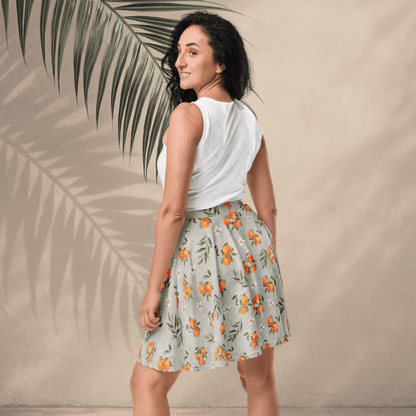 Woman wearing a white sleeveless top and floral skirt with palm leaves in the background