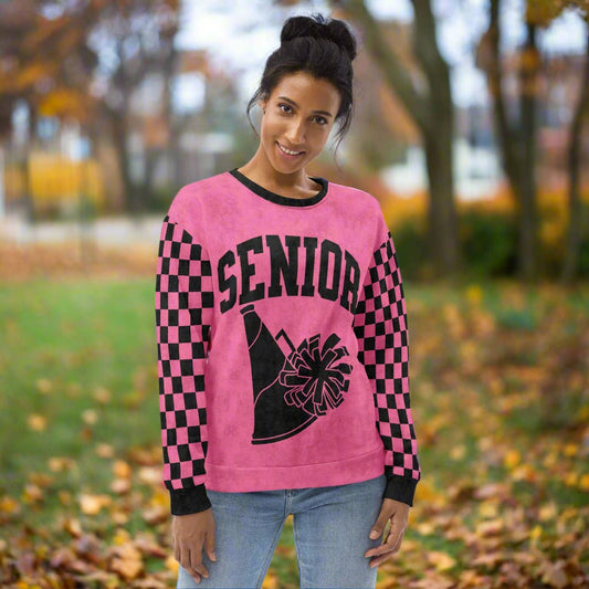 Person wearing a pink 'Senior' sweatshirt with black checkered sleeves and cheerleading graphics.