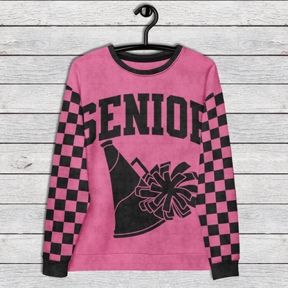 Pink sweatshirt with 'Senior' and cheerleading graphics on a wooden surface