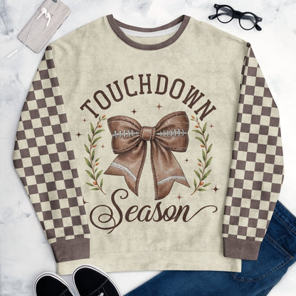 Sweatshirt with 'Touchdown Season' design featuring a bow and football, on a marble surface.