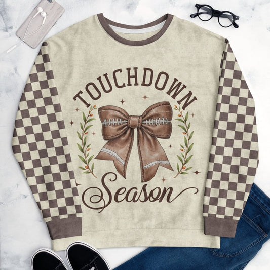 Sweatshirt with 'Touchdown Season' design featuring a bow and football, on a marble surface.