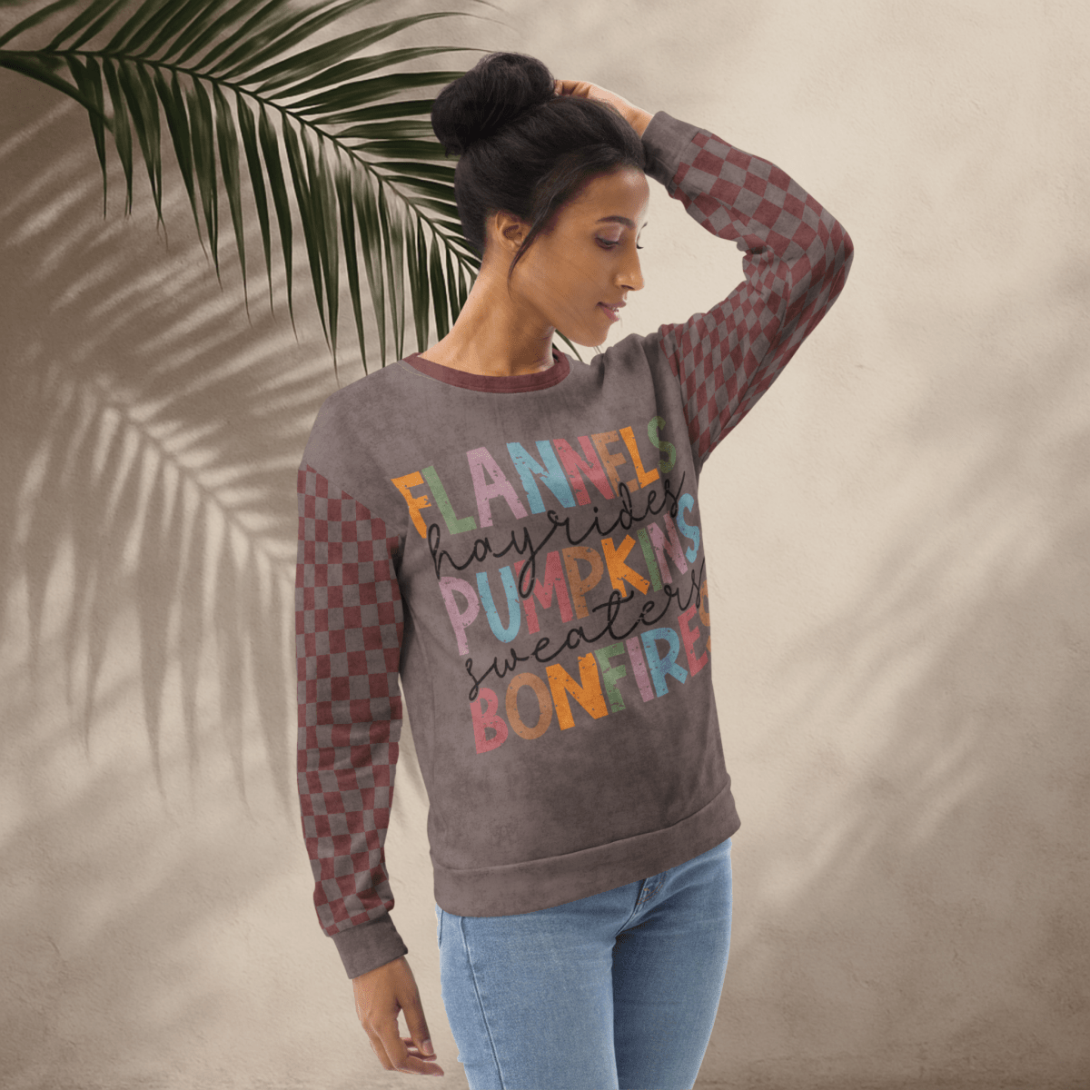 Woman wearing an espresson and burgundy crewneck sweatshirt with colorful text against a neutral background