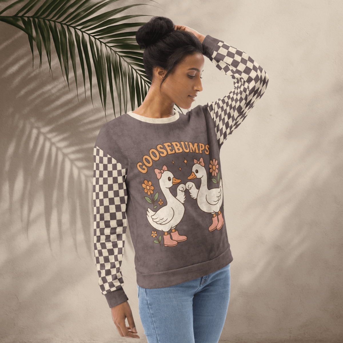 Woman wearing a sweater with cartoon geese and 'GOOSEBUMPS' text, standing against a neutral background.