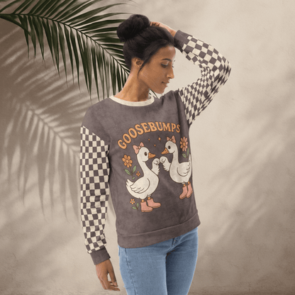 Woman wearing a sweater with cartoon geese and 'GOOSEBUMPS' text, standing against a neutral background.