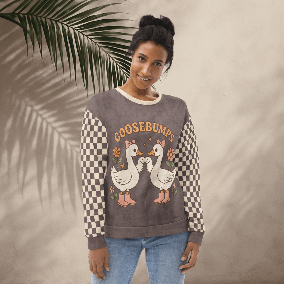 Woman wearing a sweater with cartoon geese and 'GOOSEBUMPS' text against a beige background