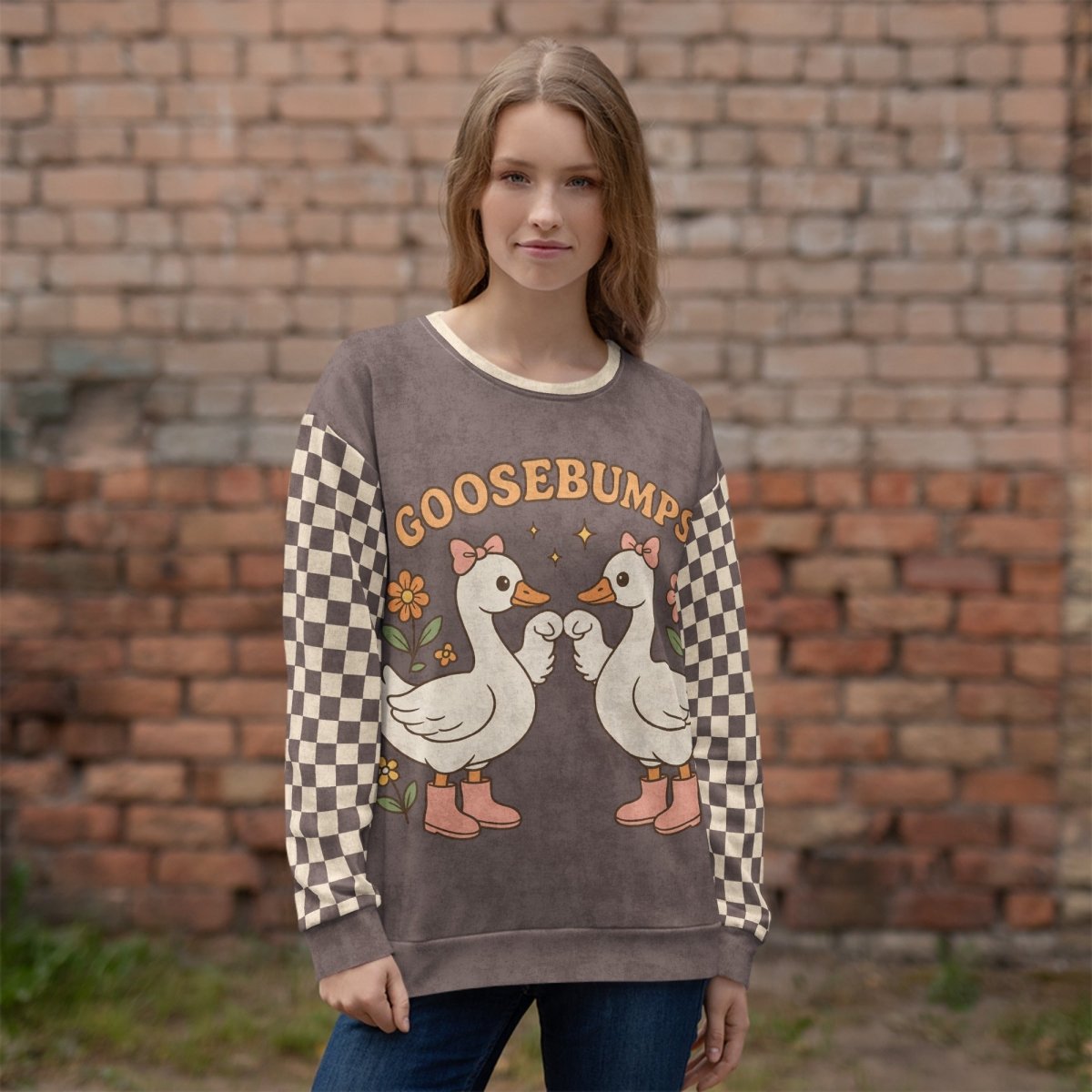 Person wearing a sweater with cartoon geese and 'GOOSEBUMPS' text against a brick wall.