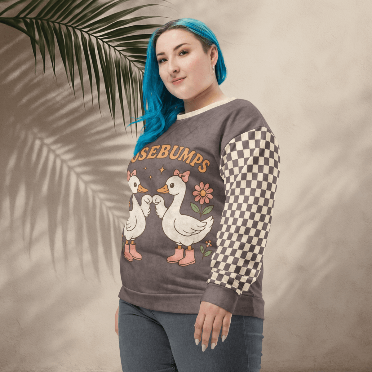 Person wearing a sweater with goosebumps graphic and checkered sleeves against a neutral background