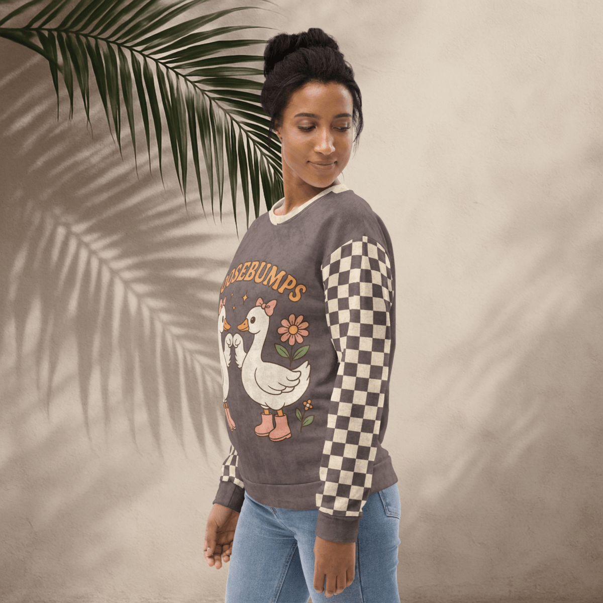 Woman wearing a sweater with a goosebumps design, standing against a neutral background with a leaf.
