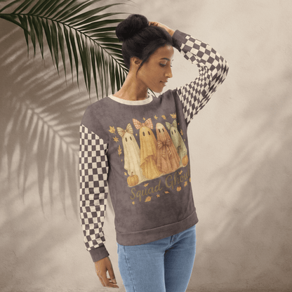 Woman wearing a sweatshirt with ghost design and checkered sleeves against a neutral background