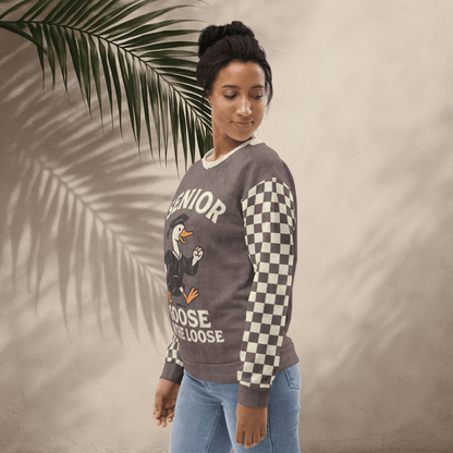 Woman wearing a sweater with 'Senior Goose on the Loose' design against a beige background