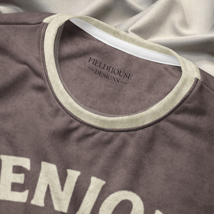 Brown shirt with 'Fieldhouse Designs' logo on a gray fabric background
