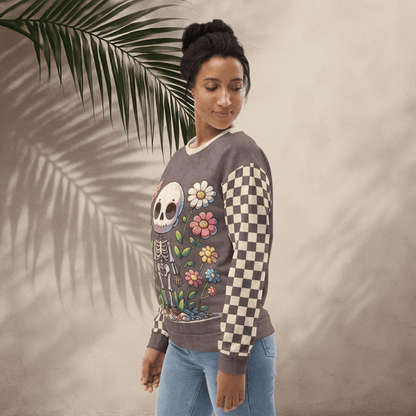 Woman wearing a sweater with a skeleton and floral design, standing against a neutral background with a palm leaf.