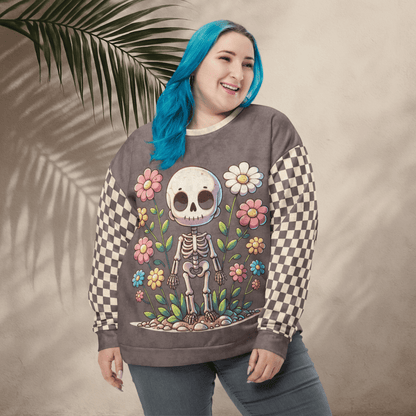 Person wearing an espresso sweatshirt with a skeleton and floral design, standing against a beige background with a palm leaf.