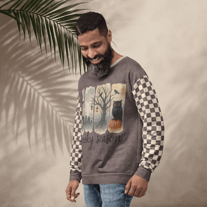 Man wearing a sweater with a checkered pattern and Spooky Season Halloween Design, standing against a neutral background with a leaf.