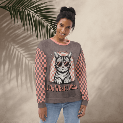 model wearing Espresso sweatshirt with a sunglasses-wearing tabby cat and “I Do What I Want” text; sleeves feature pink-and-espresso checkerboard pattern with pink collar and cuffs.
