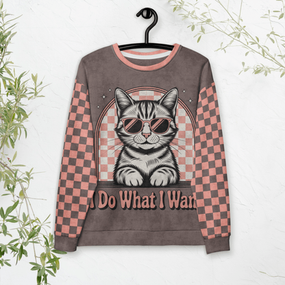 model wearing Espresso sweatshirt with a sunglasses-wearing tabby cat and “I Do What I Want” text; sleeves feature pink-and-espresso checkerboard pattern with pink collar and cuffs.