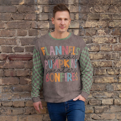 Man wearing an Espresso and sage green sweater with colorful text against a stone wall