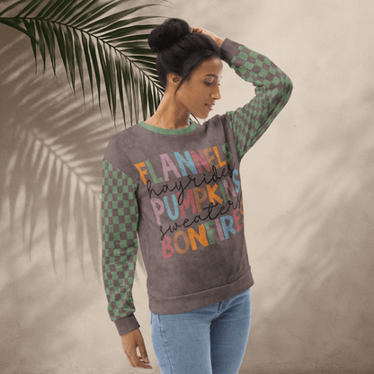 Woman wearing an Espresso and sage green colorful text sweater with a leafy background