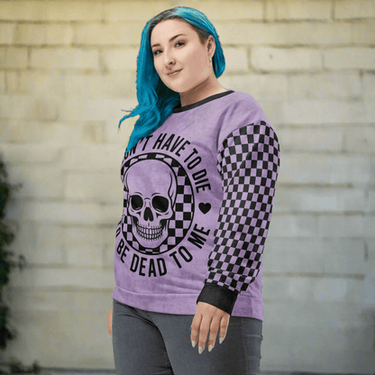 Person wearing a purple sweatshirt with a skull design and text, standing against a brick wall.