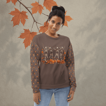 Woman wearing a brown sweatshirt with skeleton and pumpkin design, standing against a beige background with autumn leaves.
