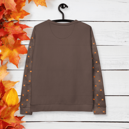 Brown sweatshirt with sleeves featuring orange pumpkin dots on a wooden background with autumn leaves.