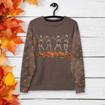 Brown sweatshirt with skeleton design and pumpkins on a wooden background with autumn leaves.
