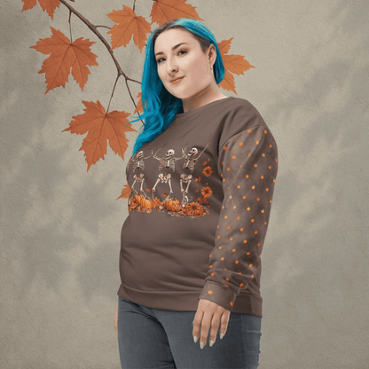 Person wearing a brown sweatshirt with skeleton and pumpkin design, standing against a neutral background with autumn leaves.