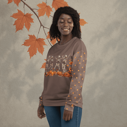 Woman wearing a brown long-sleeve shirt with skeleton and pumpkin design, standing against a neutral background with autumn leaves.