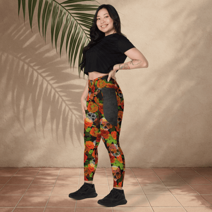 Woman wearing colorful floral skull leggings and a black crop top against a beige wall.