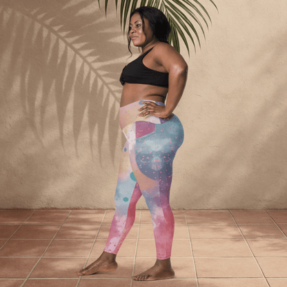 Woman wearing colorful leggings and a black sports bra against a beige wall.
