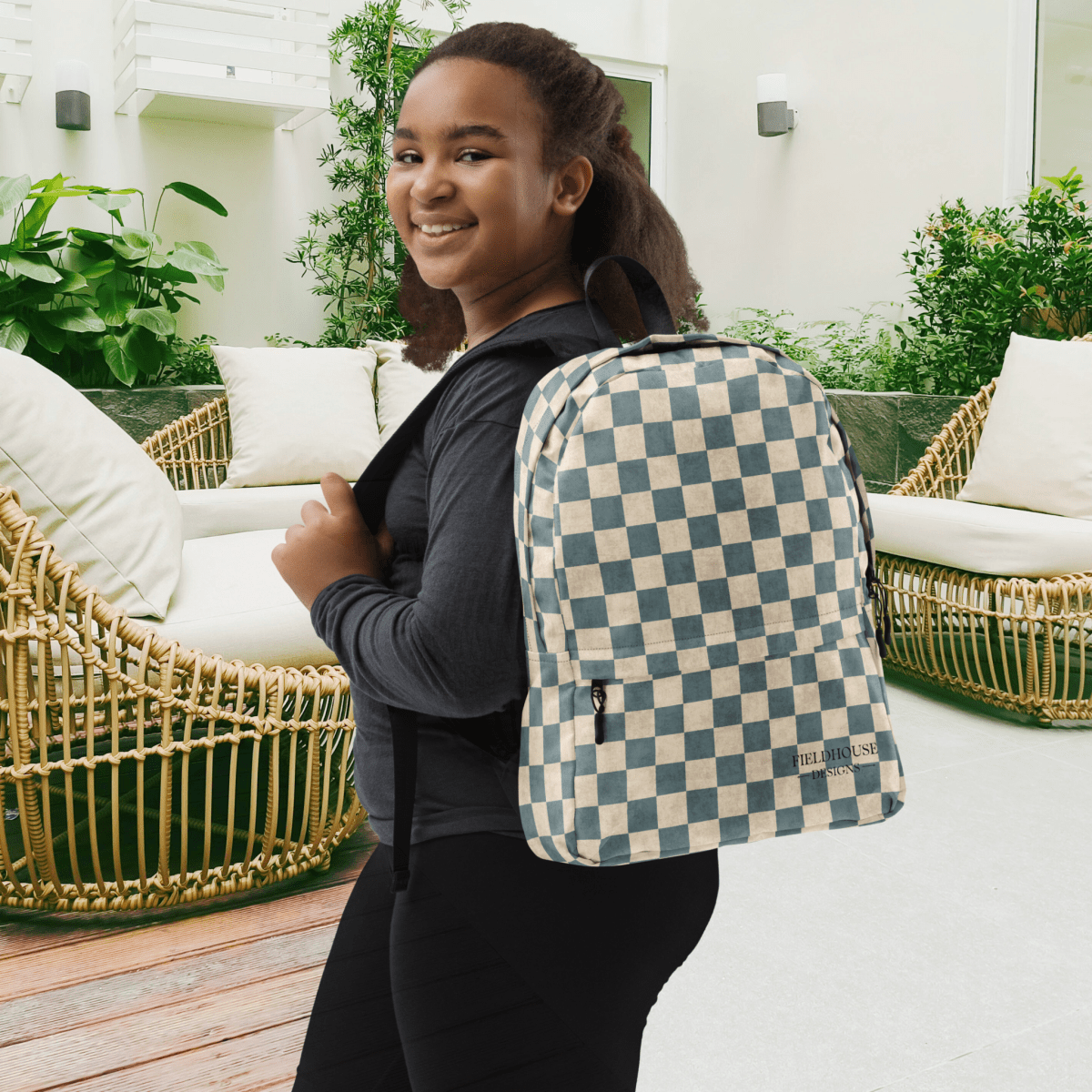 Person wearing a checkered backpack in an outdoor setting with furniture and plants.