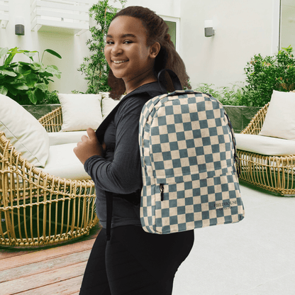 Person wearing a checkered backpack in an outdoor setting with furniture and plants.