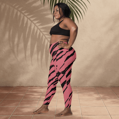 Woman wearing pink and black striped leggings against a beige wall.