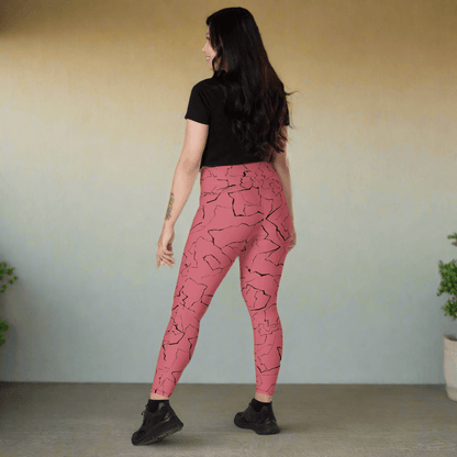 Woman wearing pink leggings with black abstract pattern on a neutral background