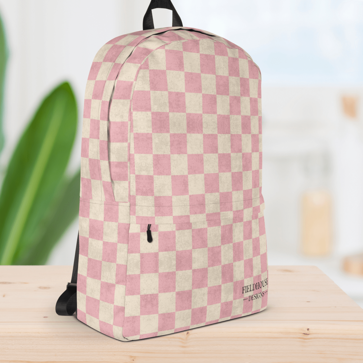 Pink and white checkered backpack on a wooden surface with a blurred background