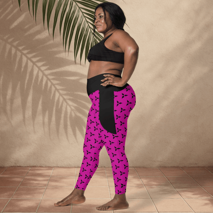 Woman wearing black sports bra and pink leggings with black patterns against a beige wall.