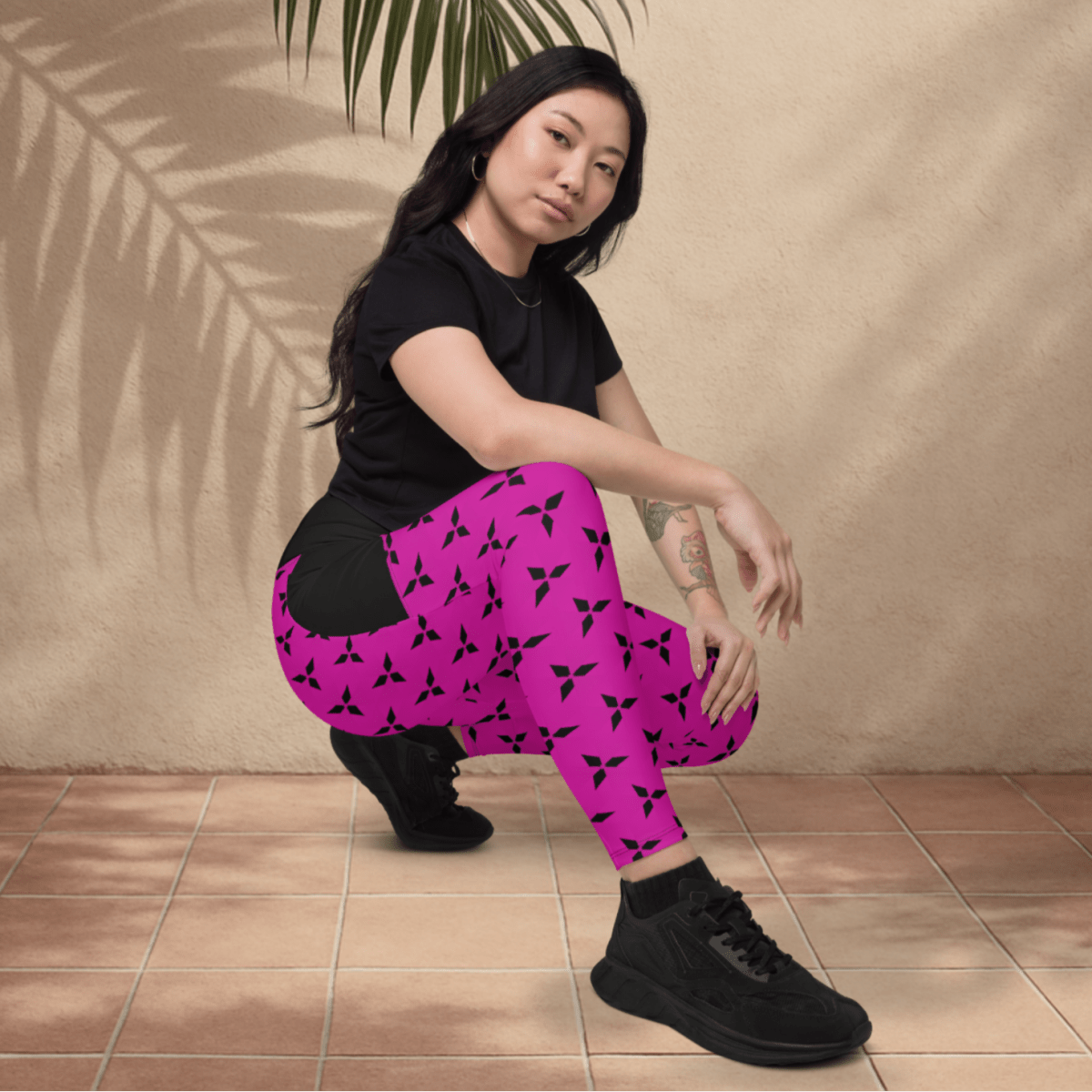 Person wearing pink leggings with black patterns and a black top, sitting on a tiled floor.