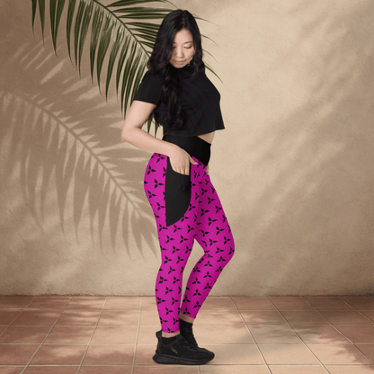 Person wearing black top and pink leggings with black patterns against a beige wall.